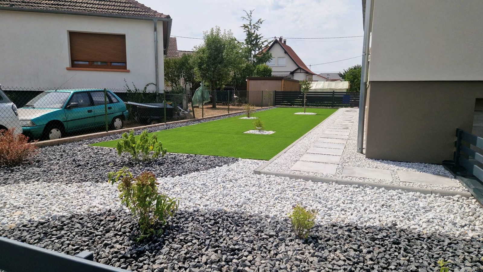 Jardin avec gazon synthétique et plantations réalisé par Jardins du Rhin
